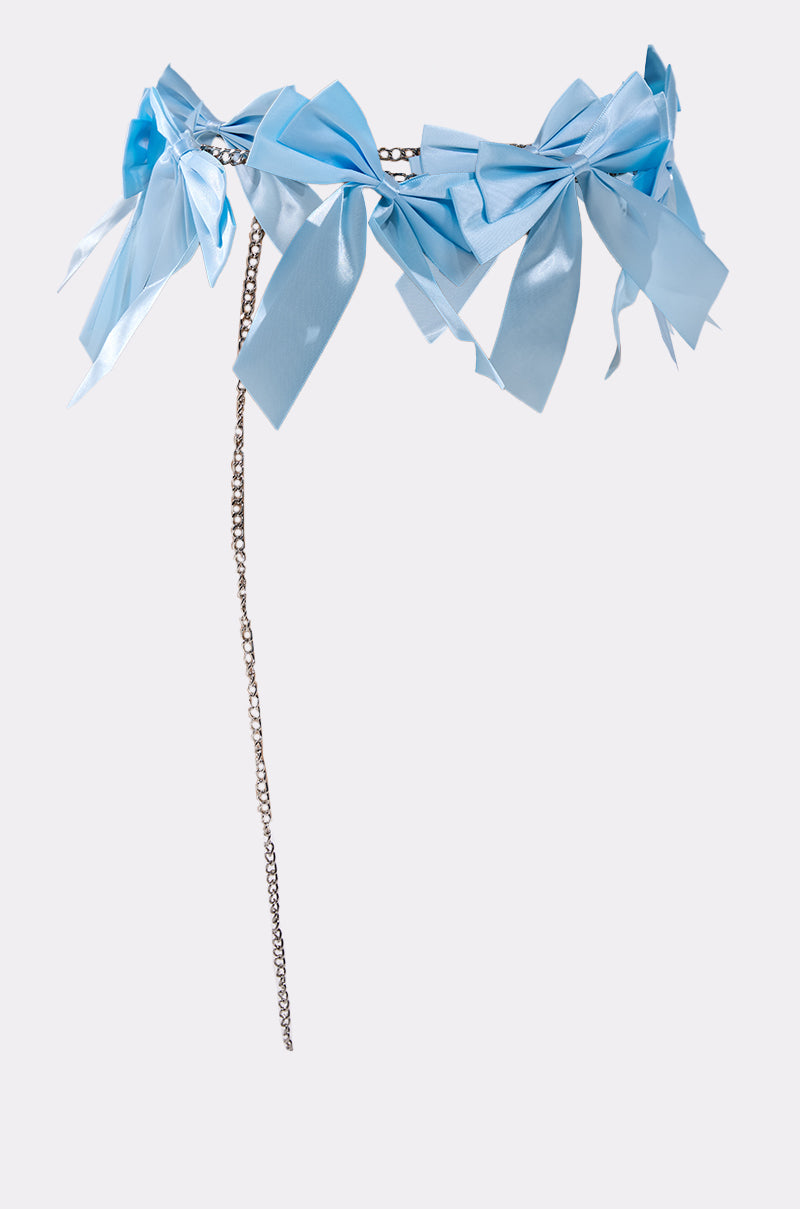 The FEMME BOW BELT features multiple light blue satin bows and a dangling silver chain, displayed against a light gray background.