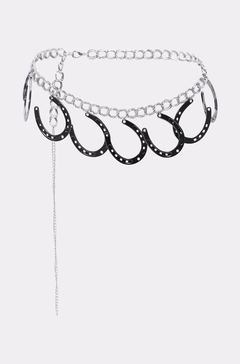 The TEST MY LUCK HORSESHOE BELT is a silver Western chain belt featuring large loops, five black metal horseshoe pendants, and a dangling thin chain—perfect for rodeo-ready looks, shown on a plain white background. 3
