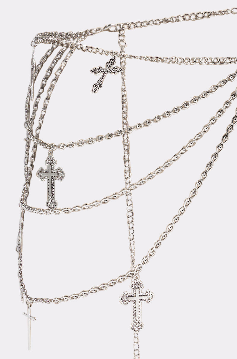 Close-up of the ON HIS BOAT CHAIN BELT, a layered silver-tone chain belt featuring ornate cross pendants, elegantly draped against a plain white background. 2