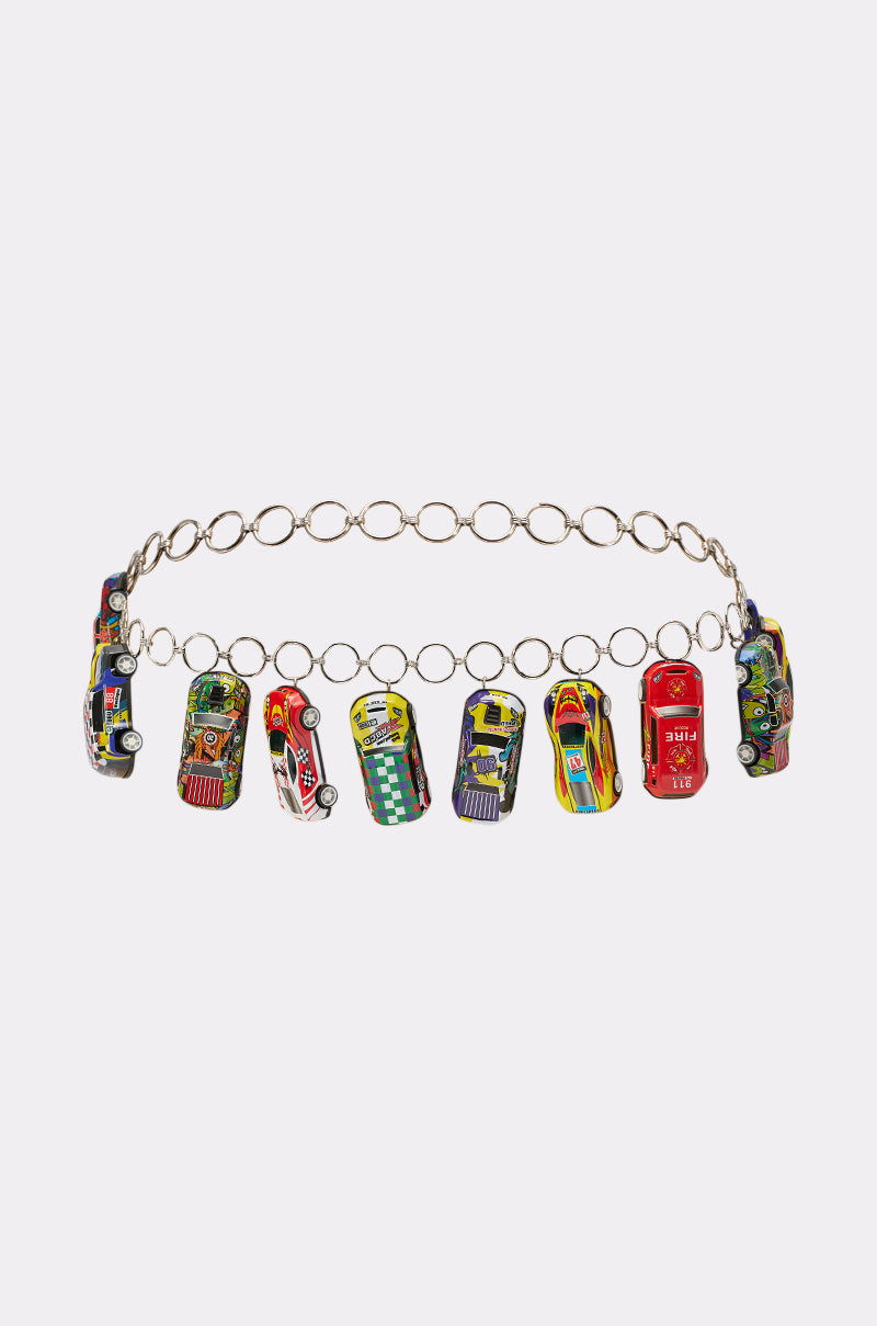 The VROOM CAR CHAIN BELT is a silver chain belt adorned with colorful miniature toy car charms, each with bright designs, creating a playful festival accessory and adding fun flair to any plain white outfit. 3