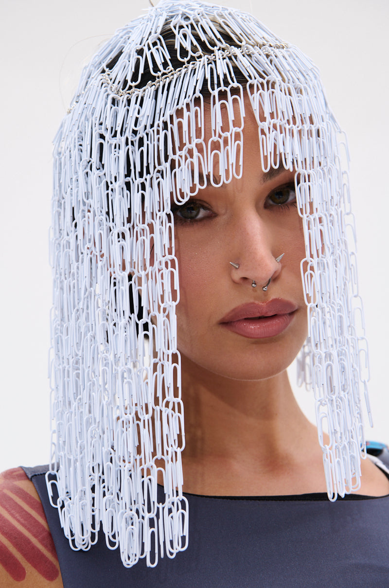 A person with nose piercings wears the IN YOUR DREAMS CLIP HAIR PIECE, which creates a metallic fringe effect over straight hair. They pair it with a sleeveless top and pose against a white background.