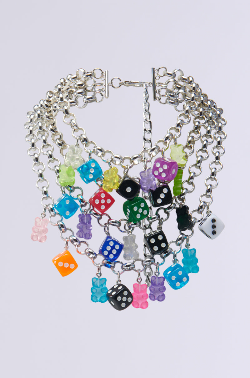 The ROLL THE DICE CHARM CHOKER is a multi-layered silver metallic base chain necklace adorned with vibrant dice and bear charms in shades of red, blue, green, yellow, and purple. It is displayed against a plain white background and includes an adjustable lobster clasp closure for a perfect fit.