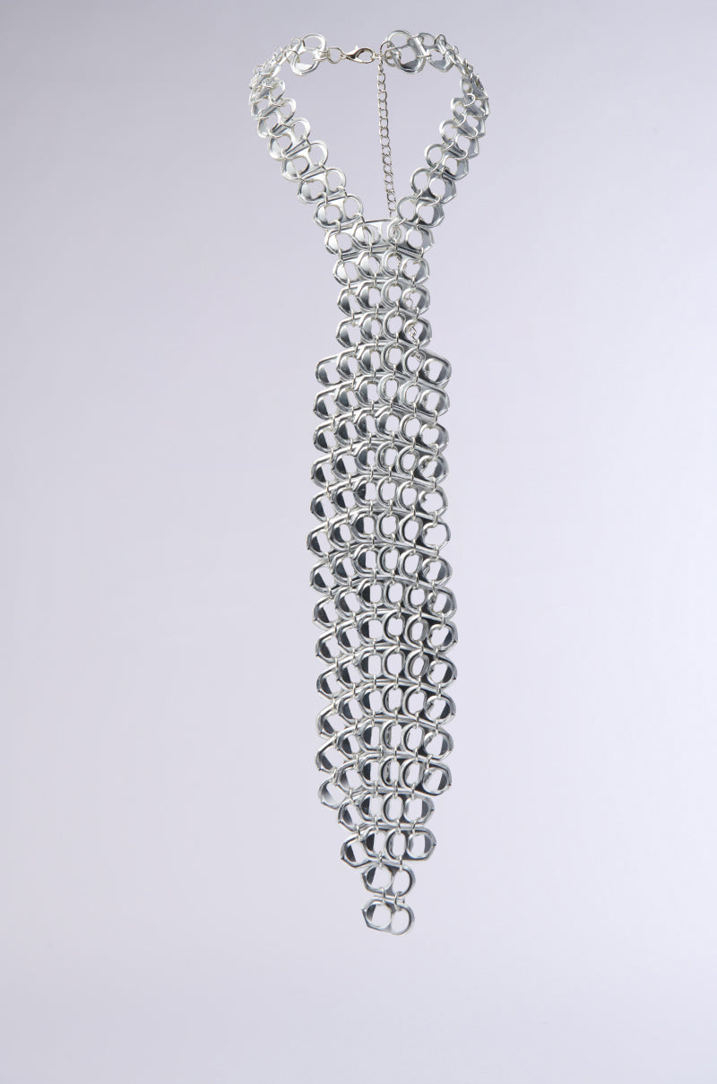 The STAY POPPIN TIE features a sculptural silhouette with interlinked faux silver metallic rings, creating a chainmail-like texture on a light gray background. This intricate design provides an industrial-chic and shiny appearance. 1