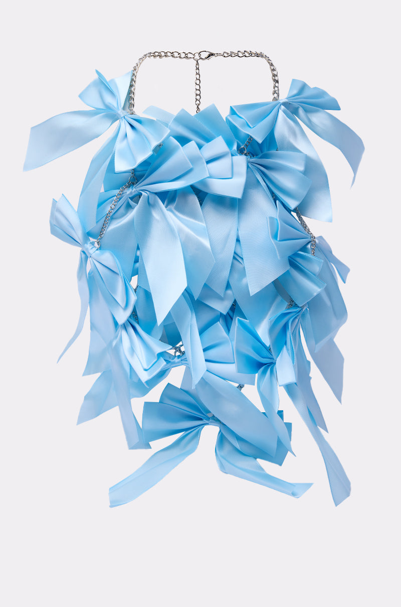 The FEMME BOW STATEMENT NECKLACE features multiple large, overlapping pastel blue satin bows on a silver chain, creating a bold and feminine accessory showcased against a plain light background.