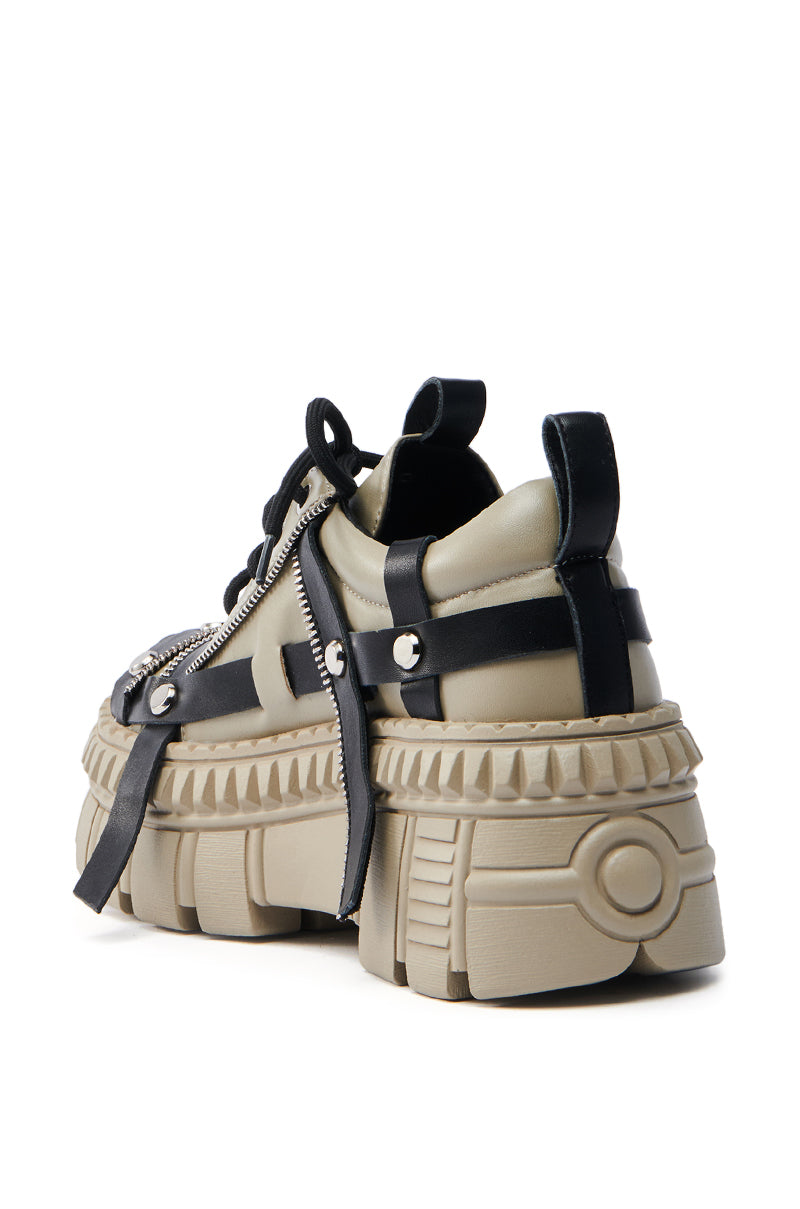 The AZALEA WANG BEAGLE KHAKI FLAT SNEAKERS feature beige flatform lug soles, chunky heels, black faux leather straps with silver buckles, laces, side zippers, and geometric midsoles. Presented against a white background.