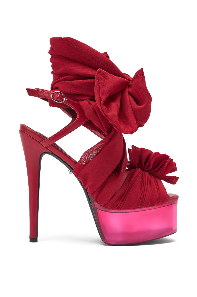 The AKIRA GOLD BEAUDEN RED PLATFORM TIE SANDAL features glossy red platform heels with wide ruched straps and two bold bows, offering a show-stopping stiletto silhouette that instantly elevates your style. 4