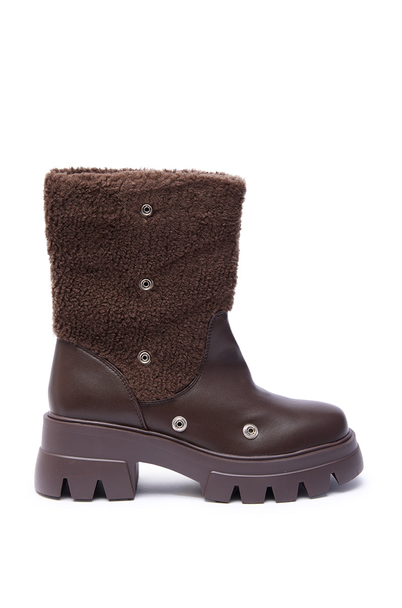 The AZALEA WANG BEHATI BROWN SHERPA BOOTIE WITH SNAP DETAIL features a chunky sole, smooth faux leather lower, and textured fleece-like upper shaft with metal snap buttons, shown in profile against a white background.