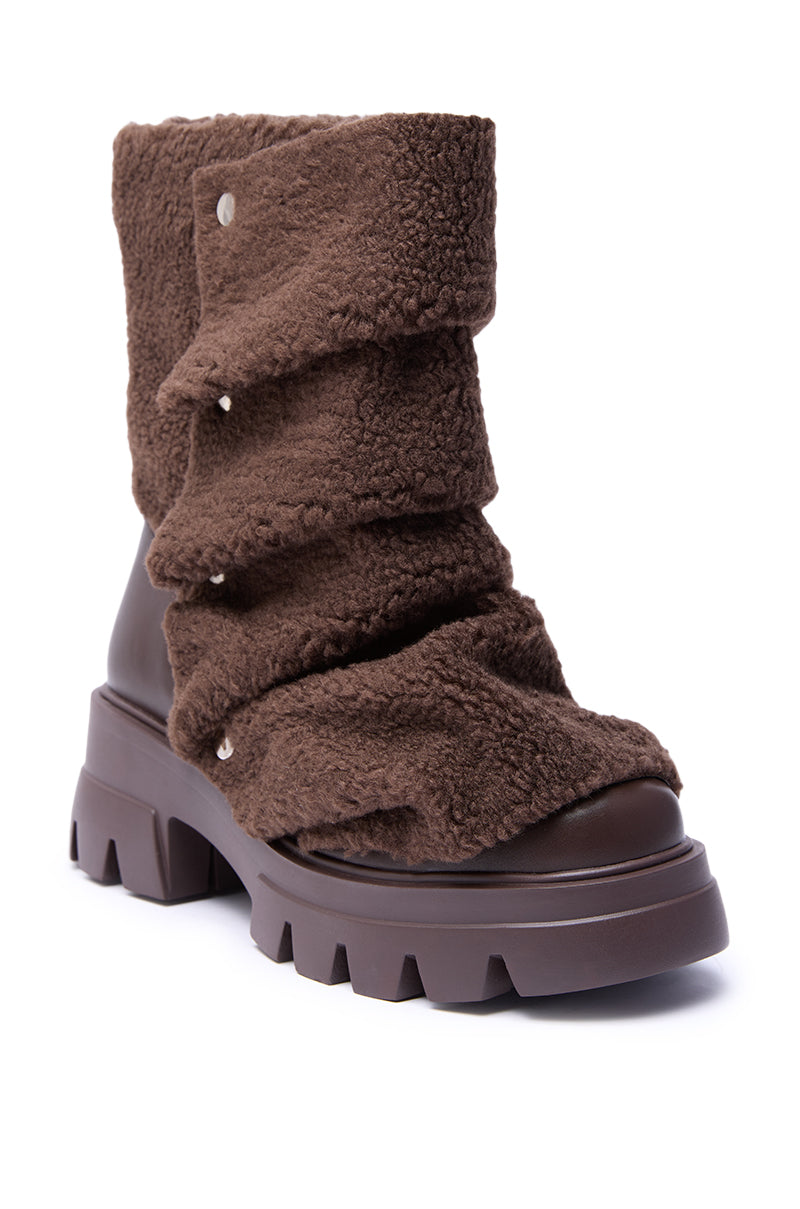 The AZALEA WANG BEHATI Brown Sherpa Bootie features layered textured faux shearling, metal snap details, a chunky heel, rounded toe, and a lug sole for added style and stability in its mid-calf design.