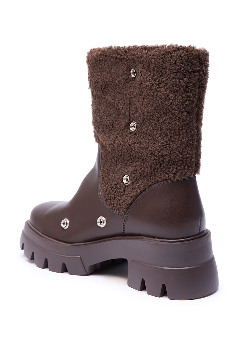 The AZALEA WANG BEHATI Brown Sherpa Bootie features a textured faux sherpa upper, chunky heel, sturdy sole, and metallic snap buttons along the side.