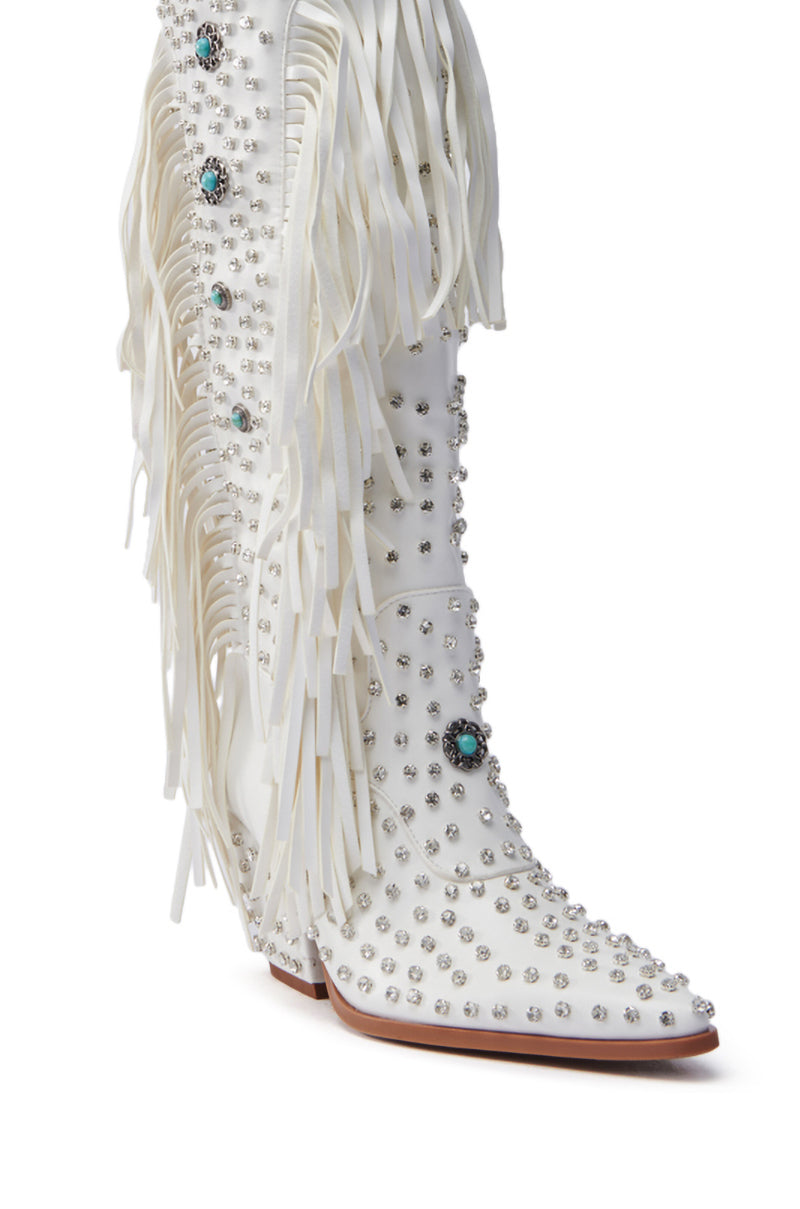 The AZALEA WANG BENNETT WHITE BOOT is a faux leather knee-high cowgirl boot, highlighted by silver studs, turquoise stones, and side fringes. Pointed toes and high heels blend Western charm with glamour effortlessly.
