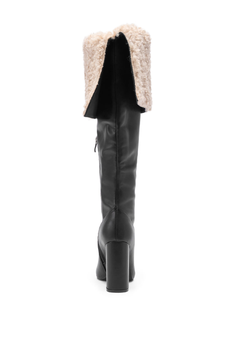 The AZALEA WANG BENOUL BLACK SHERPA LINED CHUNKY BOOT is shown from the back, highlighting its black faux leather, chunky block heel, and folded-over beige shearling cuff, all set against a white background.