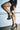 A person wearing a black faux leather mini skirt with lace-up details and AZALEA WANG BEREN BLACK HARDWARE EMBELLISHED SANDAL, standing against a light-colored garage door.