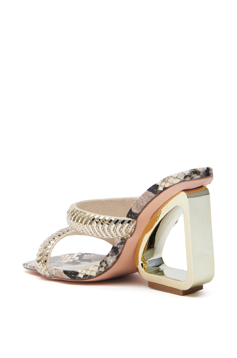 The AZALEA WANG BESSIE BROWN MULTI SNAKE WEDGE SANDAL is a stylish, high-heeled shoe featuring snake-patterned straps and a bold, hollow gold triangular faux leather heel with an intriguing center. The sole is light pink. 5