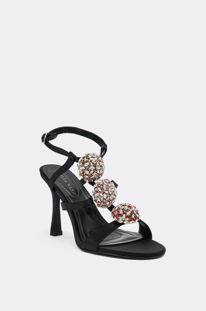 The AZALEA WANG BEST BLACK RHINESTONE EMBELLISHED STILETO SANDAL features an ankle strap and three large gold, silver, and pink rhinestone embellishments on the front straps.