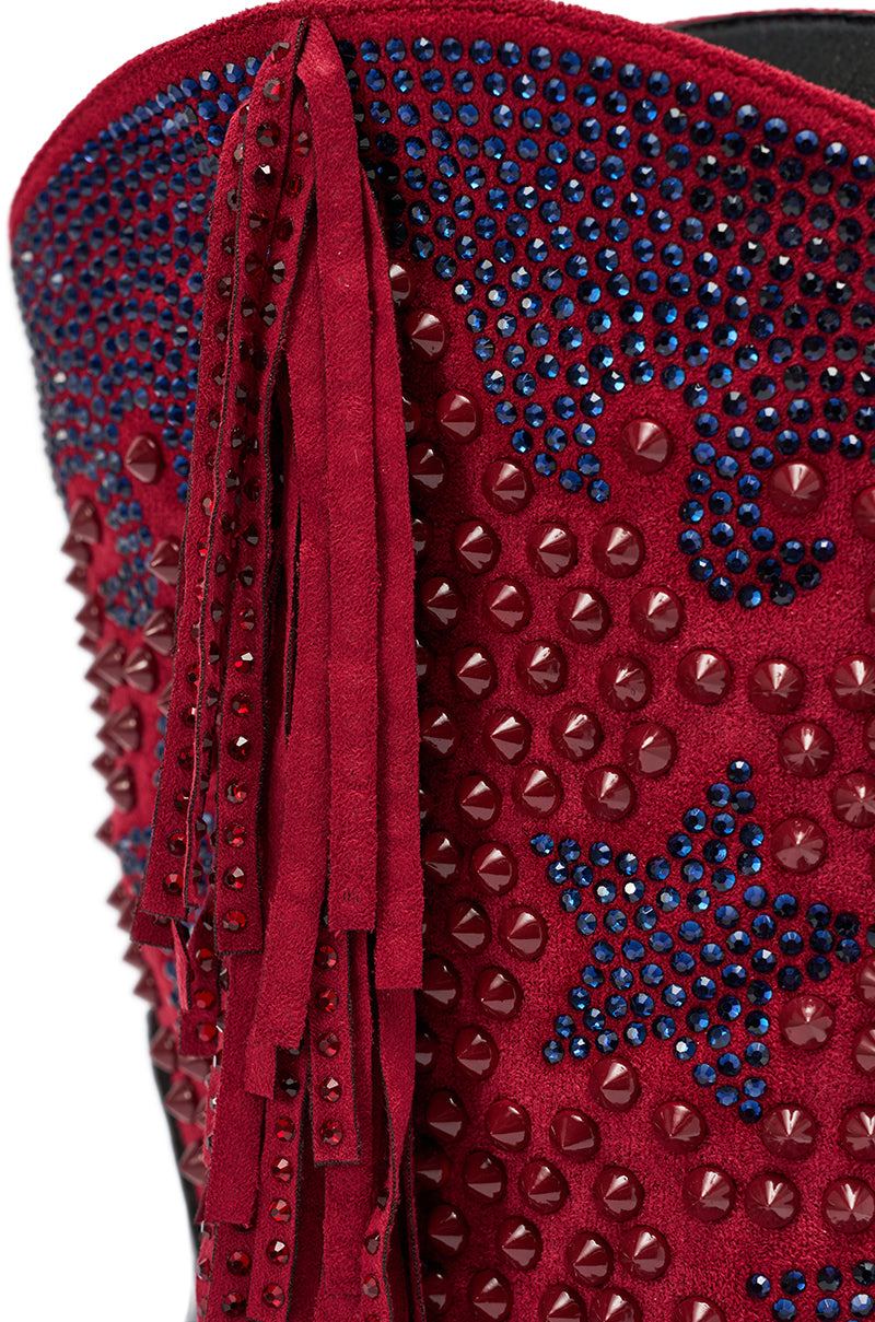 Close-up of the AZALEA WANG BETHANIE Multi Rhinestone Fringe Western Bootie in red suede, detailed with long fringe, red studs, and blue crystal star patterns—a bold statement piece.