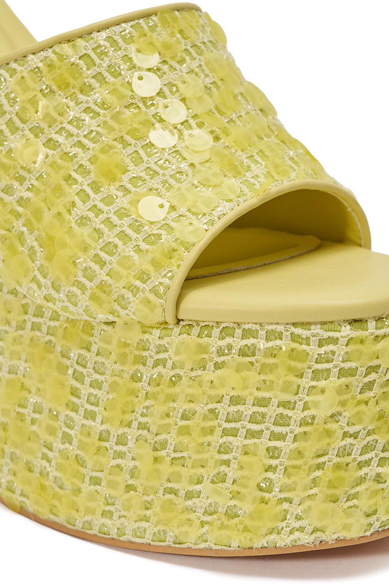 Close-up of the AZALEA WANG BETSEY YELLOW SEQUIN RAFFIA WEDGE—a yellow platform sandal with an open toe, accented by mesh-like raffia, lemon-lime sequins, and beads for a shimmering, patterned look. 7