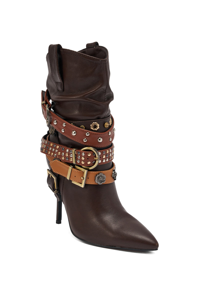 The AZALEA WANG BROWN STILETO BOOTIE is a high-heeled, dark brown leather bootie with a pointed toe, featuring embellished straps and metallic buckles around the ankle and shaft for a bold look.