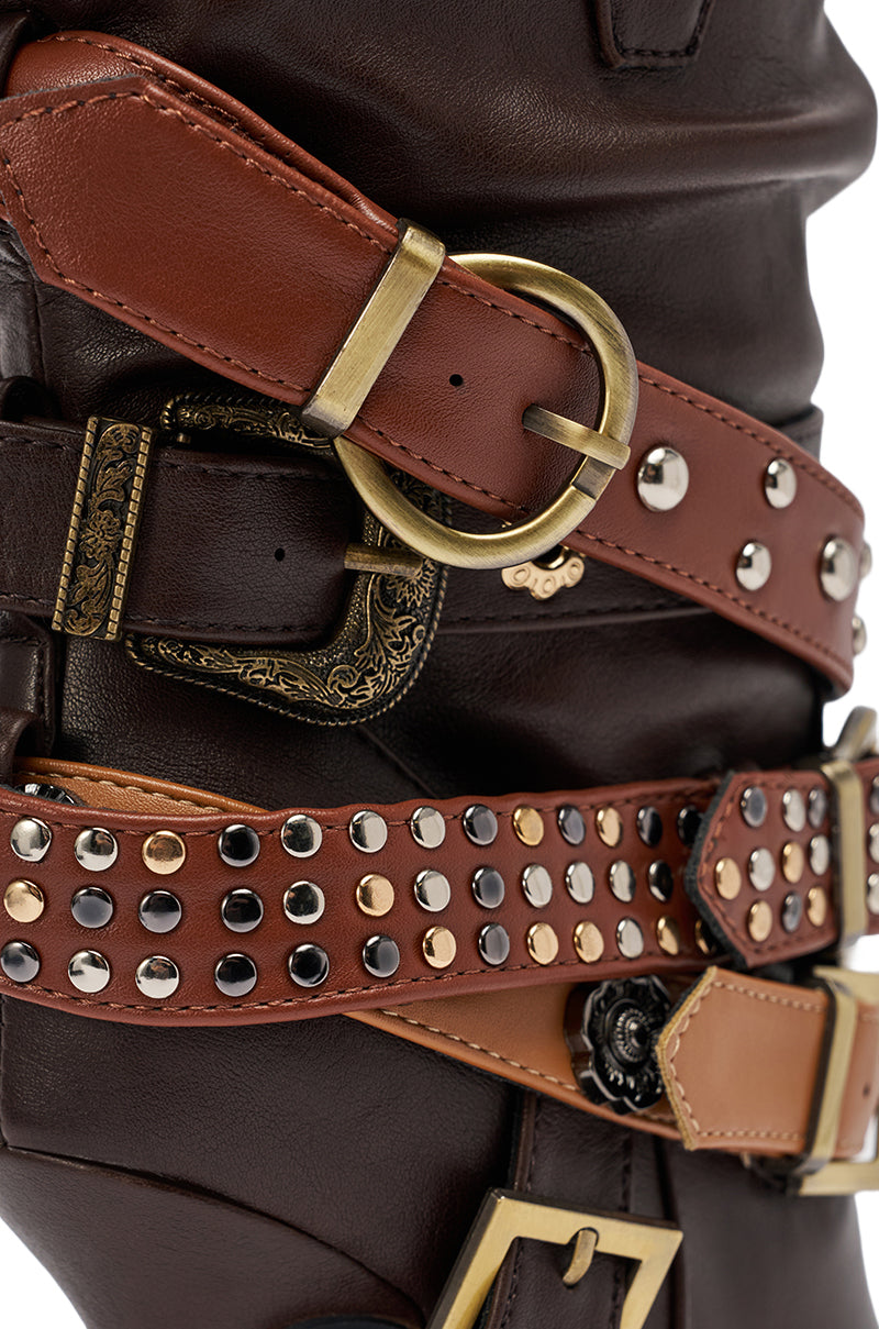 Close-up of brown leather belts with gold and brass details over dark leather fabric—perfectly complementing the AZALEA WANG BROWN STILETTO BOOTIE.