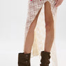 A person wears a sheer cream lace skirt with high slits and the AZALEA WANG BHARTI BROWN FLAT BOOTIE. Part of a multicolored plaid shirt is visible at the top, set against a plain white background.