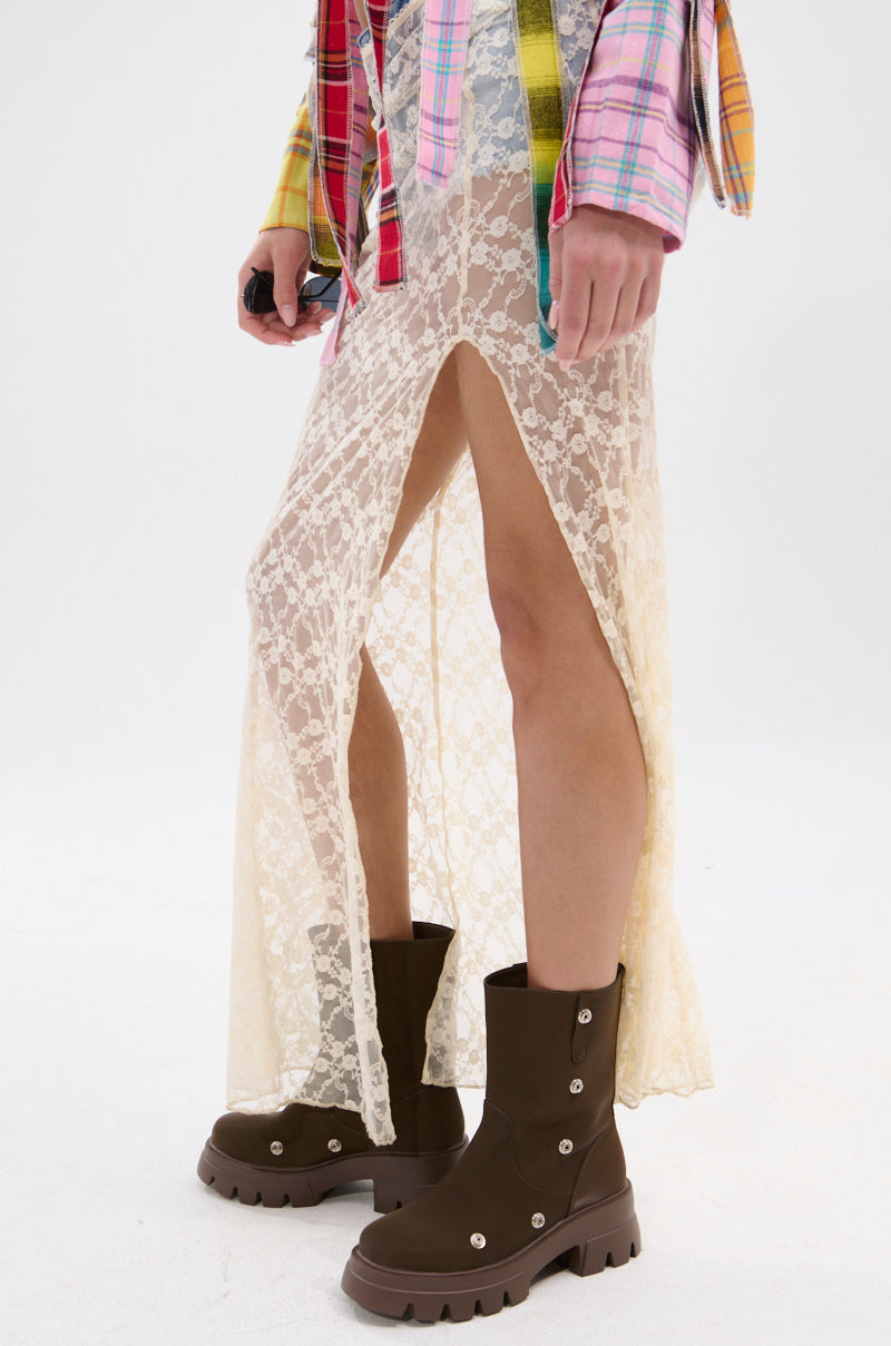 A person wears a sheer cream lace skirt with a high slit, AZALEA WANG BHARTI BROWN FLAT BOOTIE with lug soles, and a colorful plaid shirt, standing against a plain white background. 4