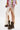 A person wears a sheer cream lace skirt with a high slit, AZALEA WANG BHARTI BROWN FLAT BOOTIE with lug soles, and a colorful plaid shirt, standing against a plain white background.