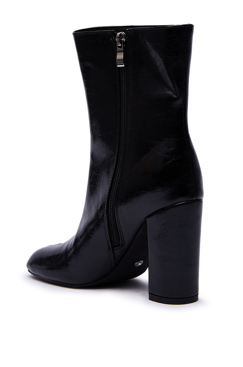 The AZALEA WANG BILHA BLACK SPLIT TOE DETAIL BOOTIE, featuring a chunky high heel, side zipper, and sleek faux leather, is displayed from a rear side angle against a white background.