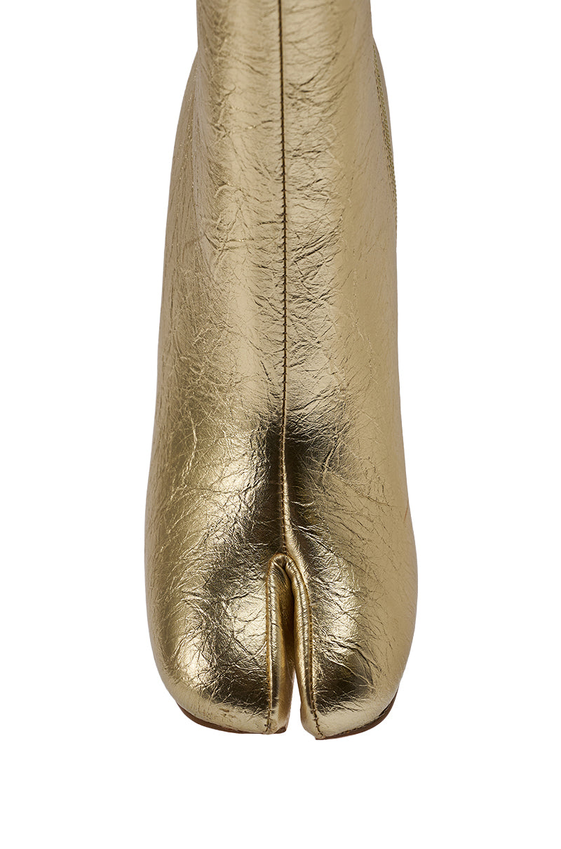 A close-up of the AZALEA WANG BILHA GOLD SPLIT TOE CHUNKY BOOTIE, showcasing its gold metallic faux leather and unique split toe design against a white background.