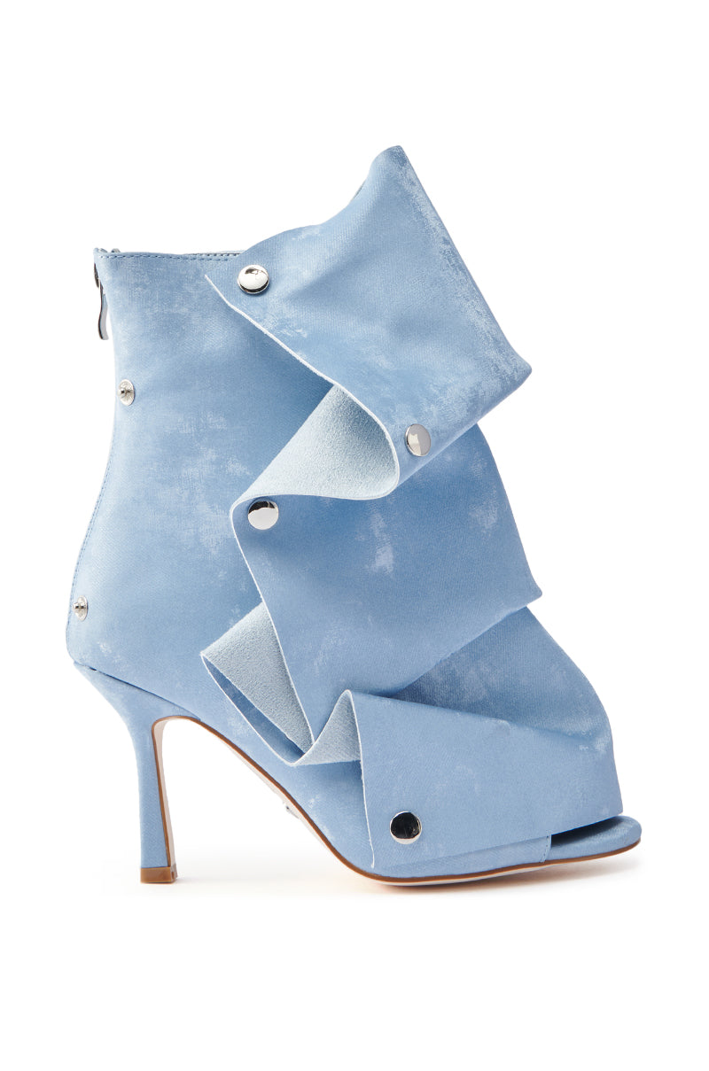 The AZALEA WANG BIRD SONG SNAP OPEN TOE BOOTIE IN BLUE is a stylish bootie with a ruffled, layered design, silver button accents, and a sleek stiletto heel. It features a textile upper and back zipper, merging elegance with unique flair.