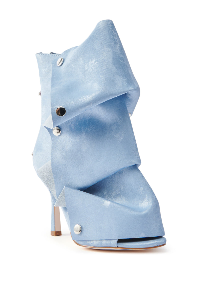 The AZALEA WANG Bird Song Snap Open Toe Bootie in Blue features a light blue abstract folded design, silver button embellishments, a stiletto heel, and a soft-textured textile upper.