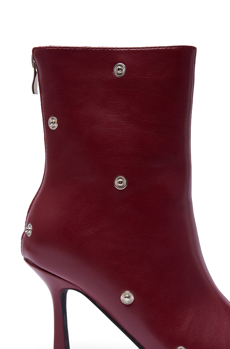 A close-up of the AZALEA WANG BIRDSONG BURGUNDY SNAP OPEN TOE STILETTO BOOTIE in rich burgundy leather, showcasing silver rivet accents, a back zipper, and a sleek modern design.