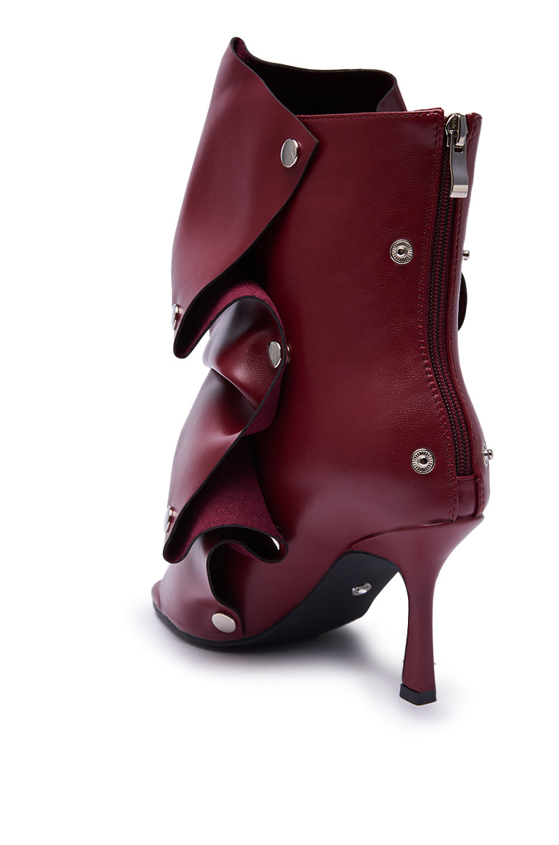 The AZALEA WANG BIRDSONG Burgundy Snap Open Toe Stiletto Bootie features sculptural layered leather, silver snap buttons, a back zipper, and is shown from a rear side angle.