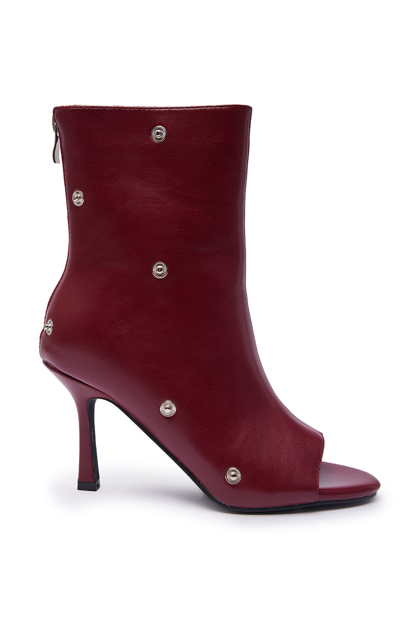 The AZALEA WANG BIRDSONG BURGUNDY SNAP OPEN TOE STILETTO BOOTIE is a leather, silver-studded, open-toe bootie with a high heel and back zipper for easy wear.