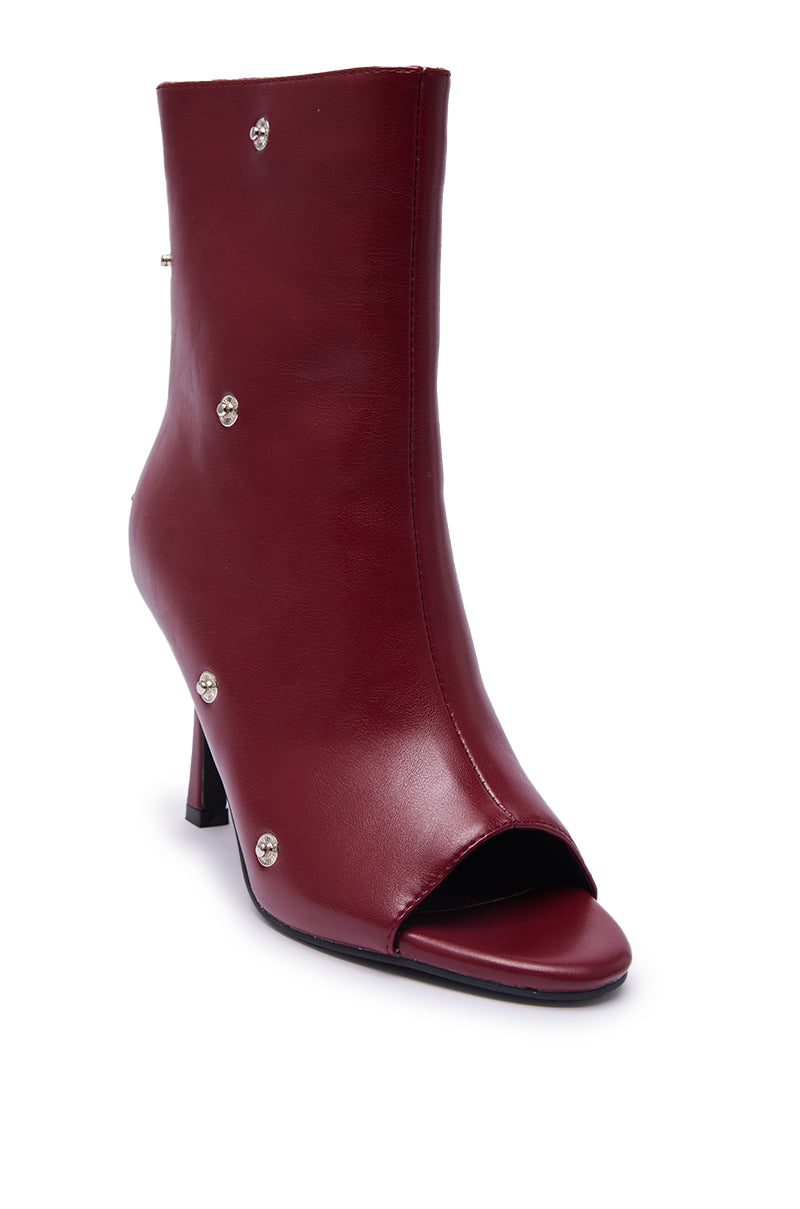 The AZALEA WANG BIRDSONG BURGUNDY SNAP OPEN TOE STILETTO BOOTIE, made of faux leather with silver side studs and an open toe, is shown against a white background.