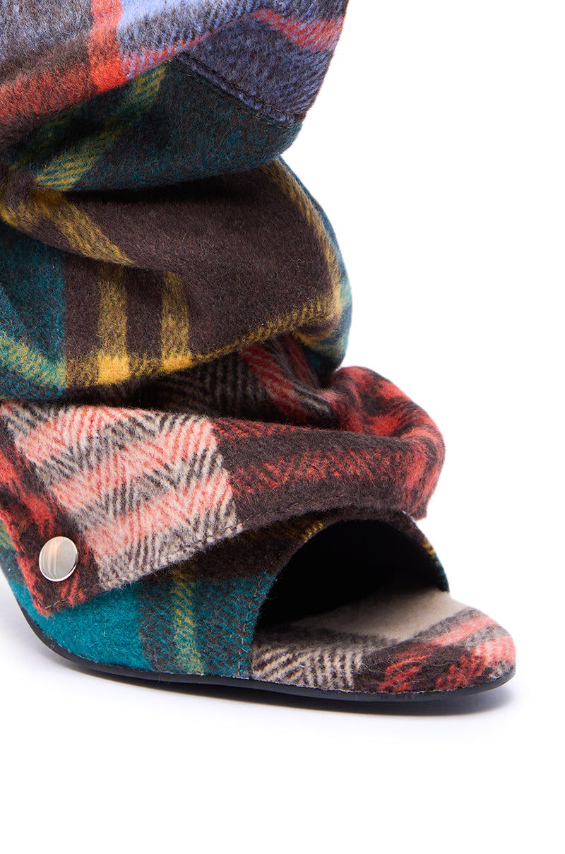 The AZALEA WANG BIRD SONG PLAID MULTI OPEN TOE SNAP BOOTIE features a multicolored plaid pattern, stiletto heel, slouchy folded design, and open toe, shown in close-up against a white background.