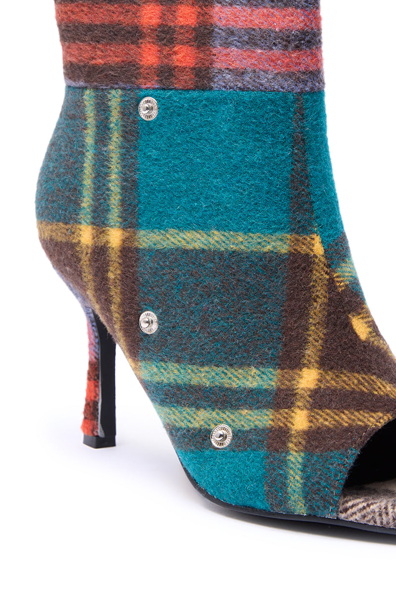 The AZALEA WANG BIRD SONG PLAID MULTI OPEN TOE SNAP BOOTIE showcases a stiletto heel, colorful teal, yellow, brown, and red plaid fabric, silver button accents, and a stylish open toe design.