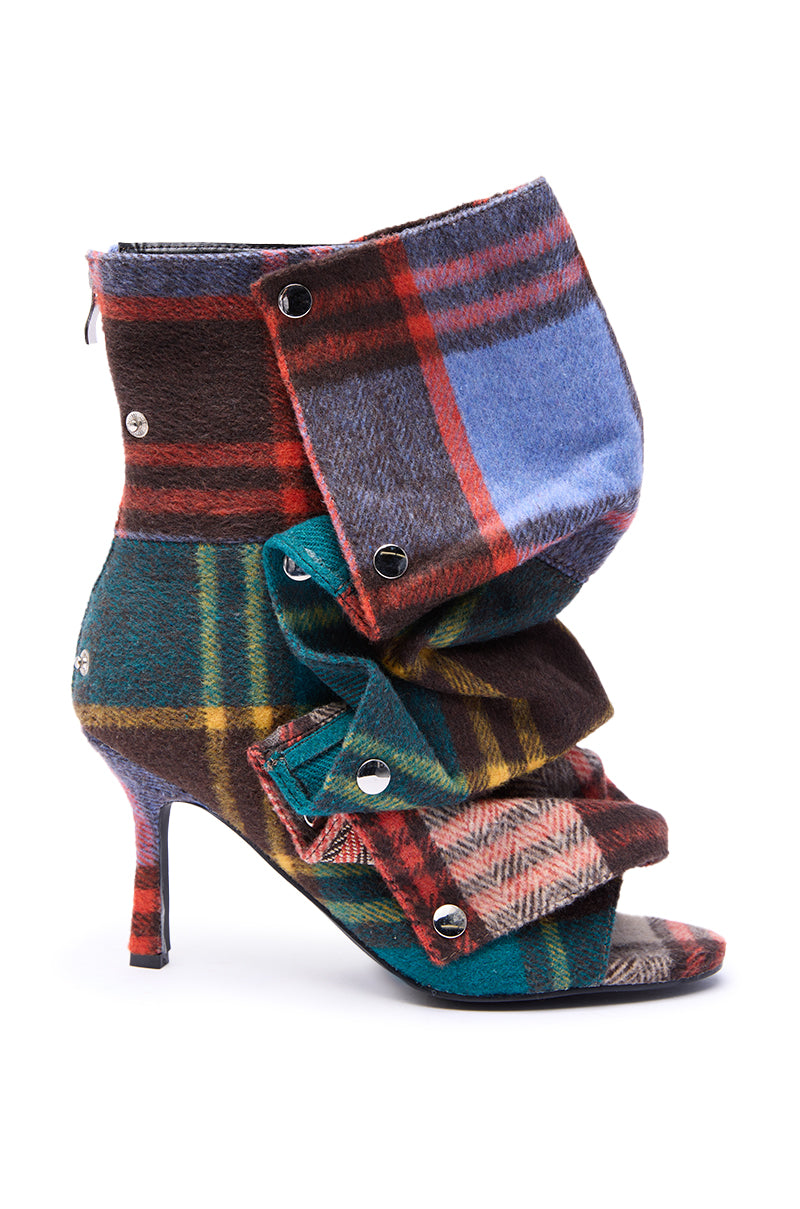 The AZALEA WANG BIRD SONG PLAID MULTI OPEN TOE SNAP BOOTIE is a high-heeled, open-toe bootie with a slouched, layered design, featuring colorful red, green, blue, and brown plaid fabric with metal snaps and a sleek stiletto heel.