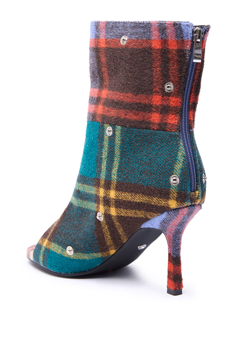 The AZALEA WANG BIRD SONG PLAID MULTI OPEN TOE SNAP BOOTIE is a high-heeled bootie with an open toe, multicolored plaid pattern, silver-tone studs, blue side zipper, and pointed stiletto heel.