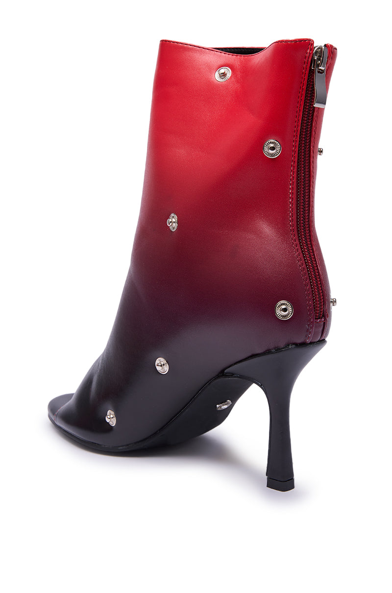 The AZALEA WANG BIRDSONG RED OMBRE SNAP OPEN TOE BOOTIE features a bold red ombre design, stiletto heel, metallic studs, peep toe, and a back zipper.