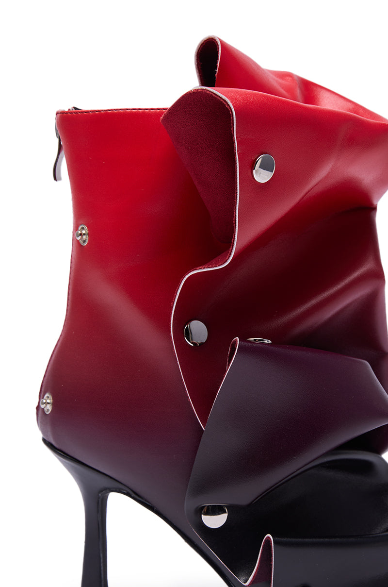 The AZALEA WANG BIRDSONG RED OMBRE SNAP OPEN TOE BOOTIE features a glossy, red-to-black ombre finish with sculptural folds, metallic rivet accents, and a chic stiletto heel for a dramatic look.