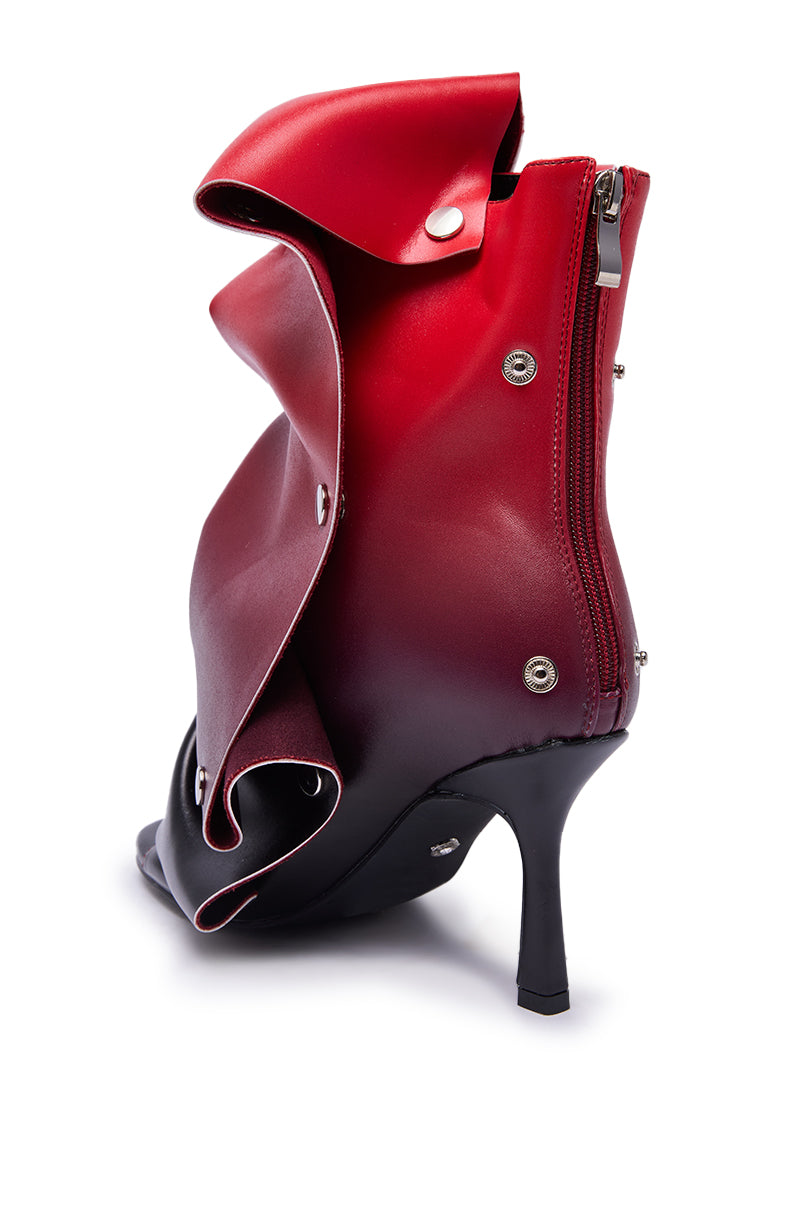 The AZALEA WANG BIRDSONG RED OMBRE SNAP OPEN TOE BOOTIE is a high-heeled, black and red faux leather stiletto with an abstract folded design, zippers, snap buttons, and an open toe.
