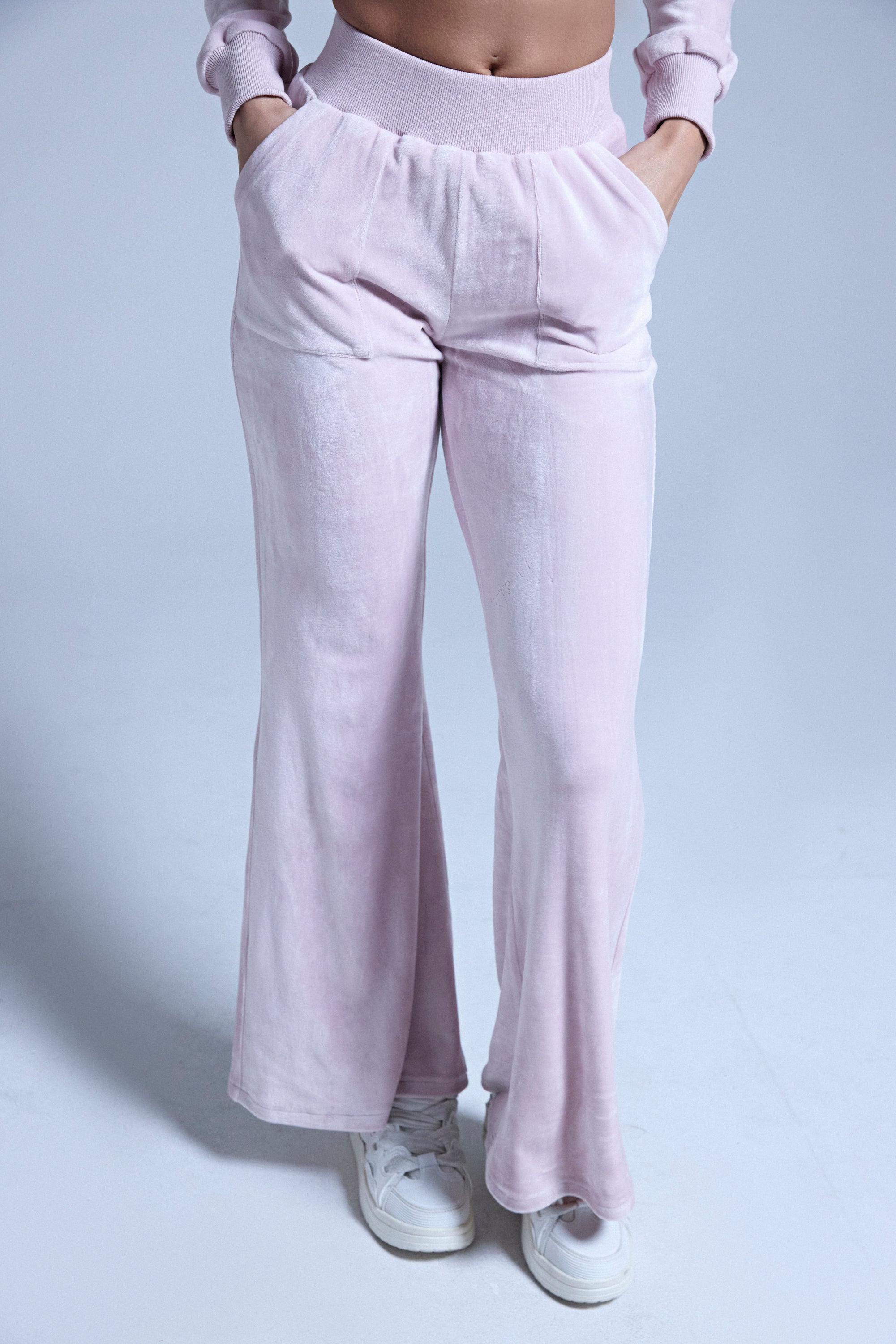 A person models the TAYLOR STRAIGHT LEG JOGGER IN PINK, standing against a plain light background with hands in pockets and paired with white sneakers. Only the lower body is visible. 1
