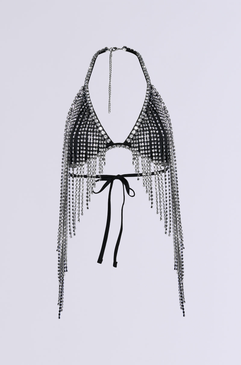 The BRING THE FUN RHINESTONE FRINGE BRALETTE TOP is a party-perfect choice, intricately adorned with clear crystals and shimmering rhinestone trim. It features long, dangling crystal strands, a halter neck design, and a tied back closure, all set against a light gray background to create a dazzling effect.