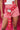 A person wears red and white checkered shorts paired with the ROSES ARE RED CIRCLE BELT, featuring cherry red faux leather and silver accents. The look is completed by a white top with red lip prints on a vibrant red background.