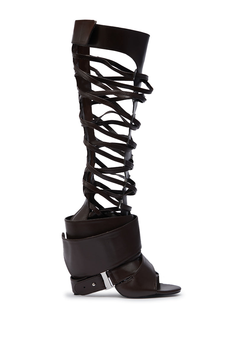 The AZALEA WANG BLACKBIRD BROWN PU STILETTO GLADIATOR SANDAL features knee-high faux leather crisscross straps, an open toe, and thick bands at the ankle and calf for an elevated gladiator look.
