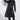 Someone wearing the RYDER FRINGE TRENCH IN BLACK MULTI with colorful fringe sleeves, matching lace-up pants, a black cowboy hat with silver details, glasses, and pointed boots.