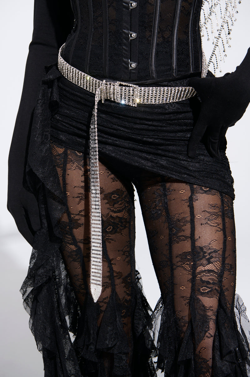 A person wearing a black lace ensemble with a corset top adorned in silver, complemented by a fitted skirt and sheer leggings. Accessories include matching gloves and the RHINESTONE BELT which features sparkling rhinestones with silver hardware, adding an elegant touch. 1