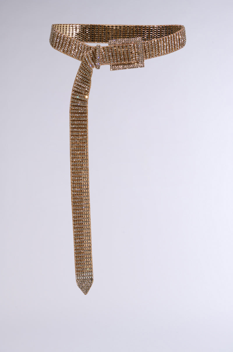 The LIKE HONEY GOLD RHINESTONE BELT is a luxurious waist accessory with a gold mesh metal design, rectangular buckle, and tie-like drape. Glittering rhinestones enhance its opulent charm against the white background.