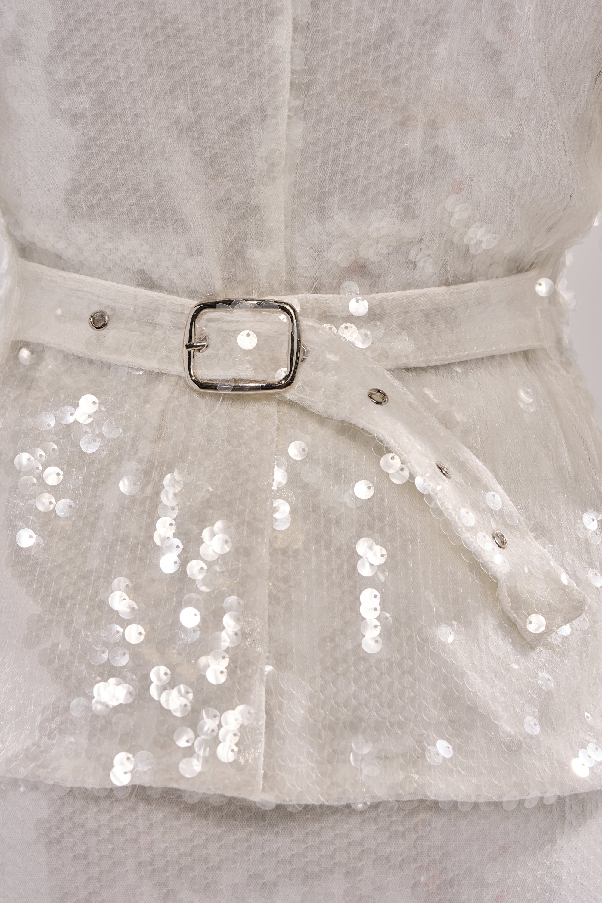 Close-up of the YOU AND ME BABY SEQUIN BUTTON DOWN, featuring white shiny round sequins, a textured fabric, and a belted back with a silver buckle. 8