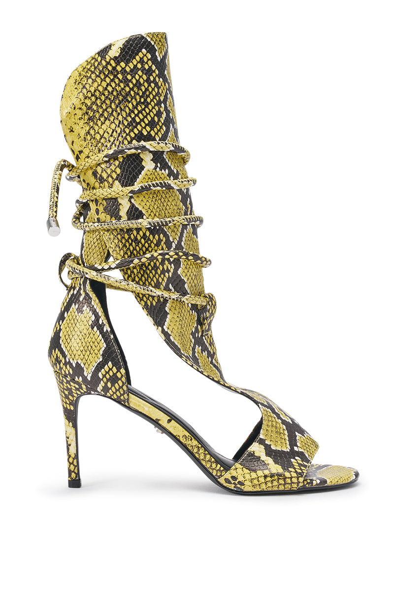 The AZALEA WANG BOCKER YELLOW SNAKE STILETTO LACE UP TALL SHAFT SANDAL features yellow and black faux snakeskin, an open toe, thin high heel, tall shaft, and a wraparound lace-up front with drawstring ankle closure. 3
