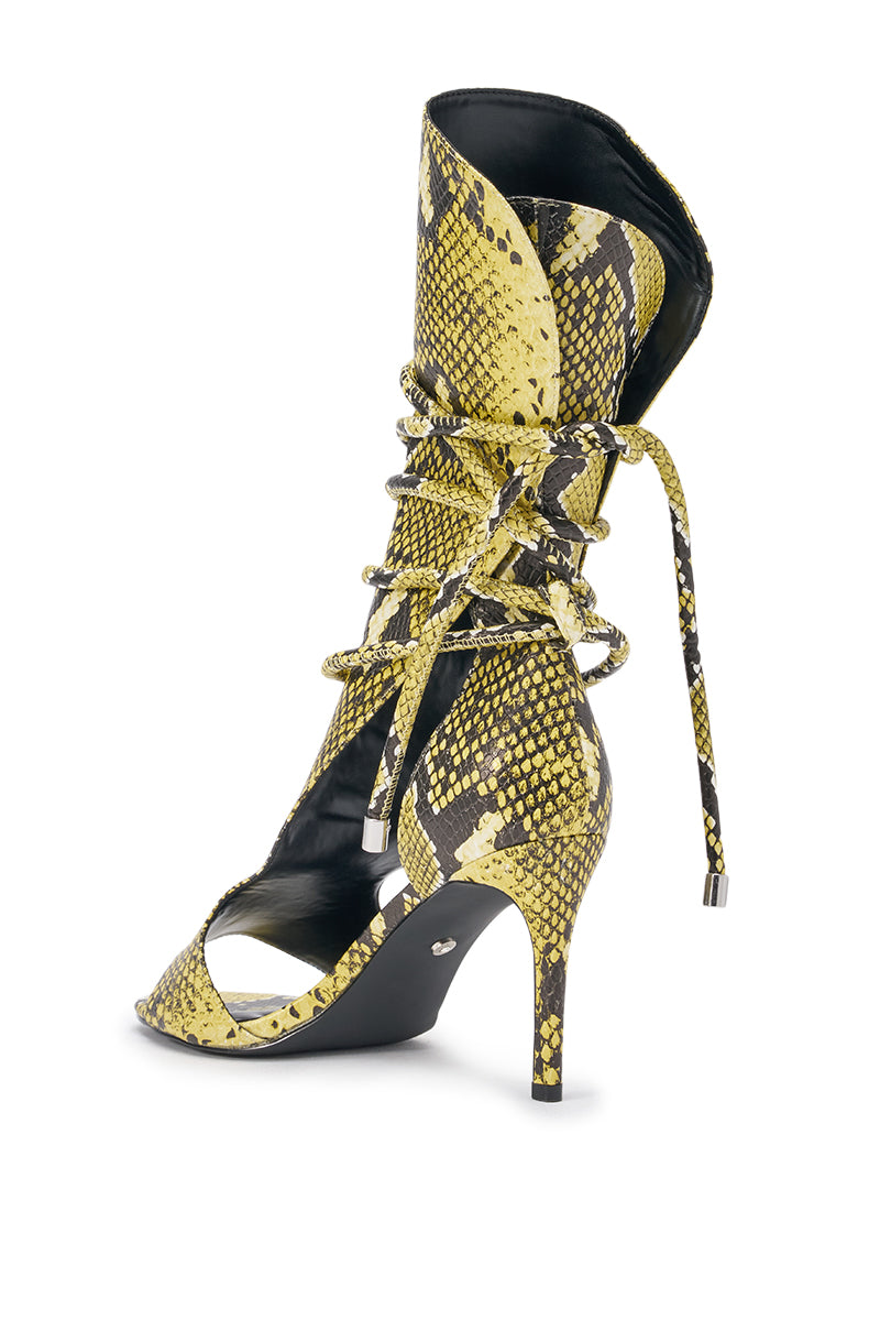 The AZALEA WANG BOCKER YELLOW SNAKE STILETTO LACE UP TALL SHAFT SANDAL is a high-heeled, open-toe faux snakeskin sandal in yellow and black, with a pointed toe, wraparound laces with metallic tips, cut-out sides, and a stiletto heel. 5